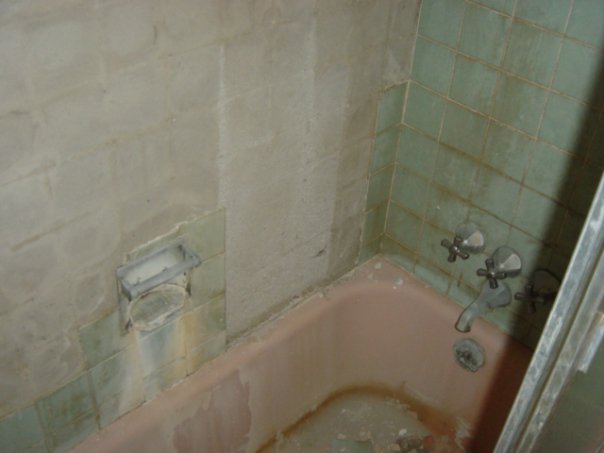 Closeup of the old bathtub and tile that had started to fall off.